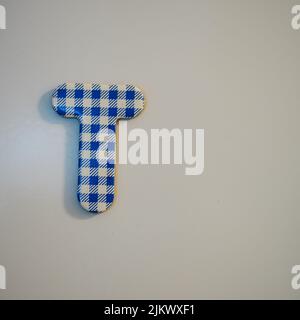 A cardboard uppercase letter 't' with gingham pattern on a gray background Stock Photo