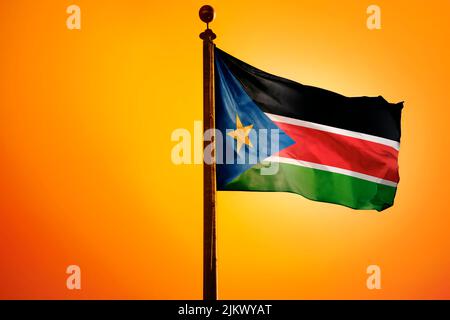 A 3D rendering of a waving flag of South Sudan on a pole on an orange background Stock Photo