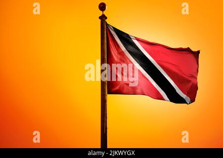 A 3D rendering of a waving flag of Trinidad and Tobago on a pole on an orange background Stock Photo