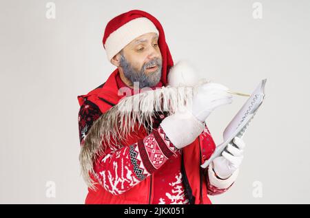 Concept nouvel an et Noël. Le Père Noël écrit avec un stylo dans un bloc-notes. Banque D'Images