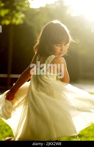 petite fille qui marche dans le parc au coucher du soleil Banque D'Images