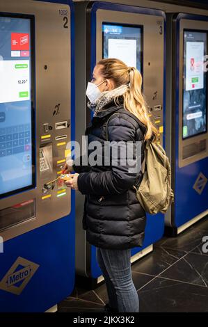 Jeune fille avec un masque achetant le billet de métro dans la machine, c'est l'hiver dans le métro de Madrid Banque D'Images