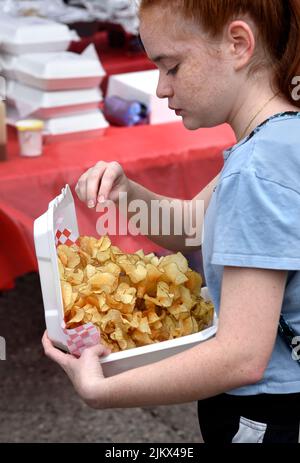 Une jeune fille achète une boîte de frites à un vendeur d'aliments lors d'un festival en plein air à Santa Fe, au Nouveau-Mexique. Banque D'Images