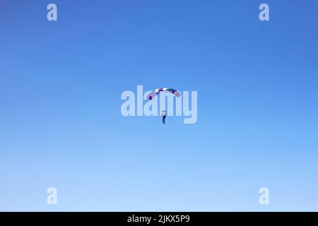 Vol d'un parachutiste expérimenté avec un parachute professionnel dans le ciel bleu, orientation et atterrissage sur précision Banque D'Images