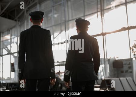 Deux pilotes mâles se tenant dans le terminal de l'aéroport Banque D'Images