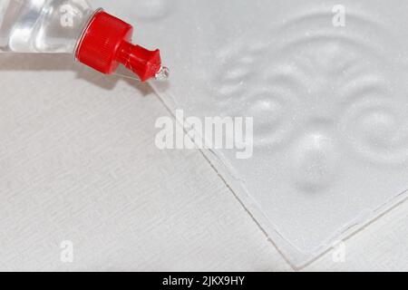 Procédé d'application de la colle universelle en vinyle d'une bouteille à la surface d'un panneau de mousse moulé blanc avant d'être collé au plafond Banque D'Images