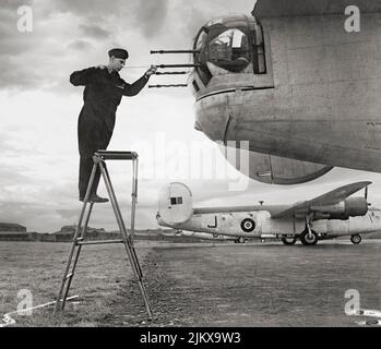 Un armourier nettoie les canons du canon de la tourelle arrière d'un Consolidated B-24 Liberator III, un bombardier lourd américain du no 120 RAF, Escadron à Aldergrove (Irlande du Nord), en avril 1943. A ses débuts, le B-24 était un design moderne avec une aile Davis très efficace montée sur l'épaule et à rapport hauteur/largeur élevé qui a donné au Liberator une vitesse de croisière élevée, une longue portée et la possibilité de transporter une lourde charge de bombe. Le B-24 a été largement utilisé pendant la Seconde Guerre mondiale, servant dans chaque branche des forces armées américaines ainsi que dans plusieurs forces aériennes alliées et marines dans chaque théâtre d'opérations. Banque D'Images