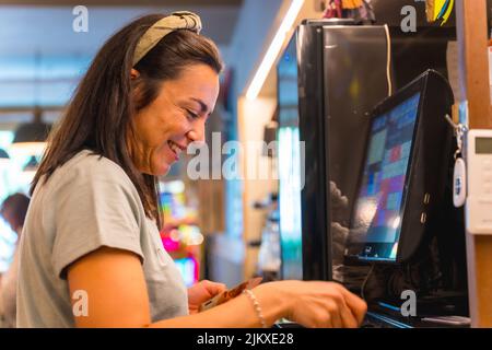 Brunette caucasien serveuse souriant faisant la vérification sur l'ordinateur dans le café Banque D'Images