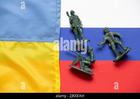 Le drapeau de l'Ukraine et de la Russie et les drapeaux russes sont des soldats en plastique éparpillés pour les enfants, la guerre russo-ukrainienne Banque D'Images