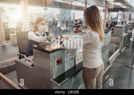 Une employée d'aéroport donne un passeport et un billet d'avion à une dame Banque D'Images