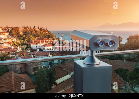 Télescope optique touristique sur le point de vue de la terrasse d'observation surplombant la vieille ville de la station avec des toits d'orange pendant un coucher de soleil coloré dans la ville d'Antalya Banque D'Images