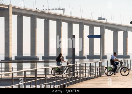 Two cyclists along the Vasco da Gama bridge in Parque das Nacoes, Lisbon Stock Photo