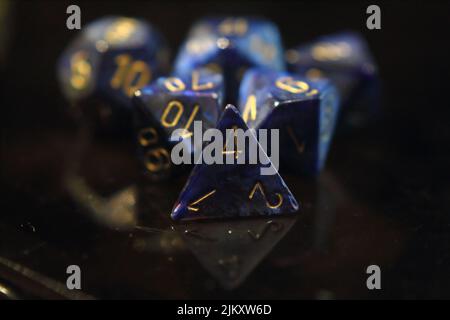 Blue metallic swirled dice with gold numbers on the reflective surface Stock Photo