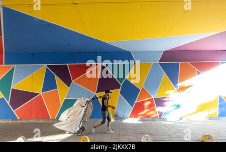 Employé informel de recyclage traînant un grand chariot tiré à la main dans les tunnels colorés avec des peintures murales. Collecteurs de déchets recyclables à Istanbul, Turquie Banque D'Images