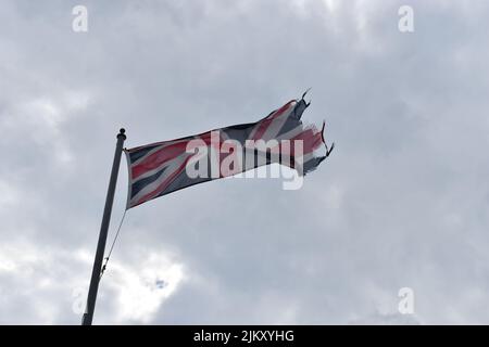 Un drapeau Union Jack en lambeaux contre un ciel nuageux. Banque D'Images
