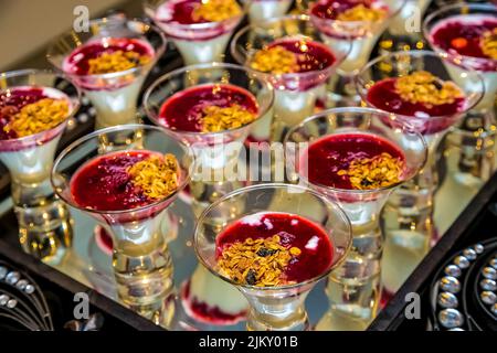 Un gros plan de délicieux desserts dans des tasses en verre sur un plateau métallique Banque D'Images