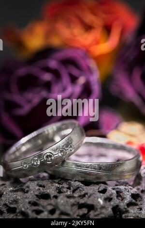 A closeup shot of two silver elegant rings with a colorful bouquet in the background Stock Photo