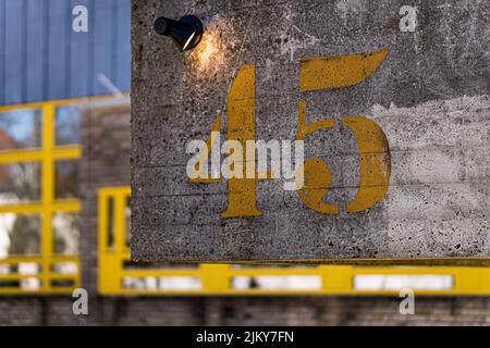 A closeup shot of yellow number forty five on concrete wall Stock Photo