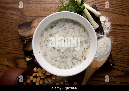 A top view shot of a milk soup or porridge with beans spilling from a pot on a wooden table Stock Photo