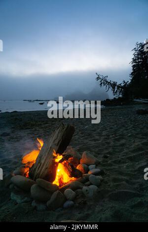 Un feu de camp chaud et orange sur la plage contre la brume et le crépuscule de rassemblement, côte nord, Parc national olympique, Washington Etats-Unis Banque D'Images