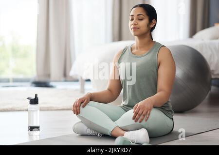 Changez d'avis, d'attitude et d'humeur. Une jeune femme sportive méditant à la maison. Banque D'Images