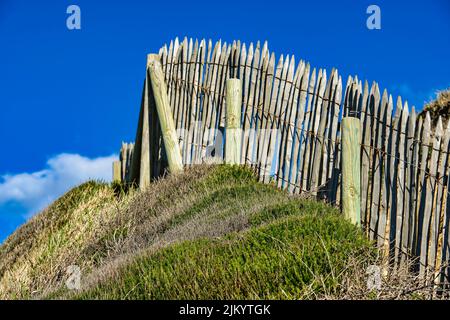 A closeup of wooden fence on hill against a cloudy blue sky Stock Photo