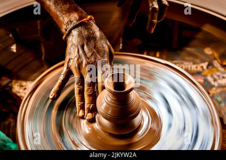 Photo à vitesse d'obturation lente d'une main de potier faisant un pot à partir d'une roue de poterie. Banque D'Images