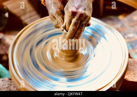 Photo à vitesse d'obturation lente d'une main de potier faisant un pot à partir d'une roue de poterie. Banque D'Images