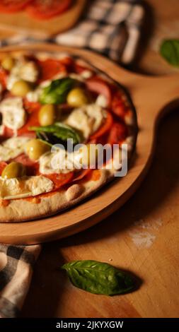 A vertical shot of a freshly made pizza margarita on a wooden board Stock Photo