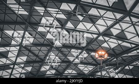 A low angle shot of a modern, symmetrical roof with triangular windows and a lamp in the spotlight Stock Photo