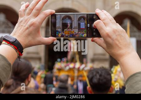 Barcelona, Catalonia, Spain - April 10, 2022. Man taking a photo with his cell phone at the passage of the Borriquita in Barcelona (Spain), selective Stock Photo