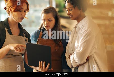 Directeur de supermarché utilisant une tablette numérique tout en discutant avec ses employés lors d'une réunion du personnel. Groupe de femmes diverses travaillant ensemble dans Banque D'Images