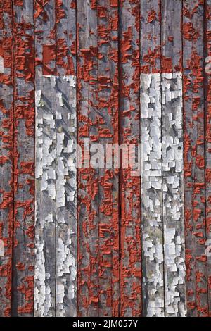 Gros plan de la peinture rouge et blanche qui s'écaille sur le parement de la planche en bois. Banque D'Images