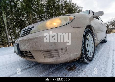 A closeup shot of a grimy car on the snowy road Stock Photo