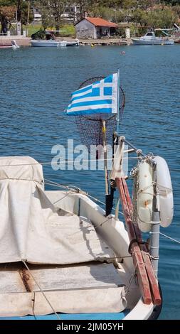 A vertical shot of a Greek boat in the harbor on the Peloponnese, Greece, with a flag and lifebuoys Banque D'Images
