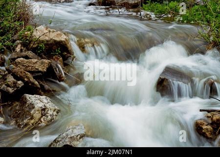 A long exposure shot of a flowing beautiful rocky stream Stock Photo