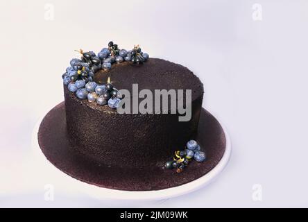 Gâteau de velours foncé doux désert avec bleuets frais haut d'or isolé sur blanc Banque D'Images