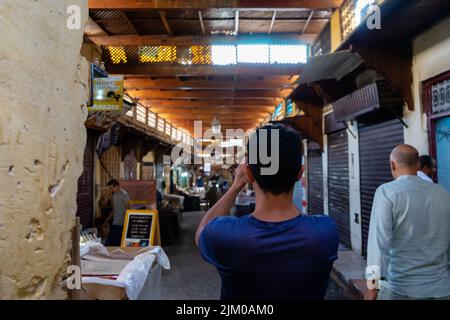 Visitor taking photos in the old medina of Fes Banque D'Images