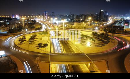 A long exposure shot of Kuwait Towers and square at night with the lights of the city Stock Photo