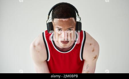 La musique me permet de rester concentré. Portrait court d'un jeune homme de basket-ball de belle pose en studio. Banque D'Images