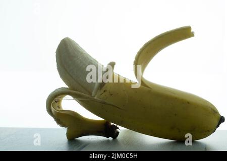 A closeup shot detail of a half-peeled banana isolated with a white background Stock Photo