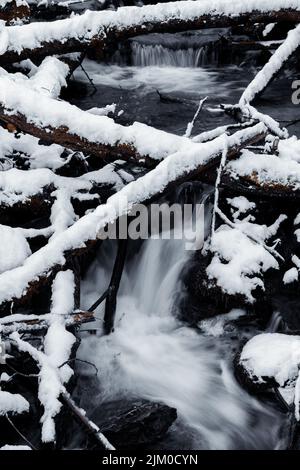 Un plan vertical d'une cascade qui coule le long des rochers couverts de neige en hiver Banque D'Images