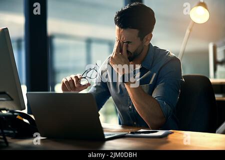 Lutte contre le stress professionnel. Photo d'un jeune homme d'affaires stressé pendant une nuit de travail tardive. Banque D'Images