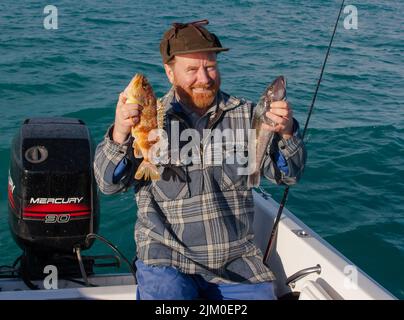 Un regard sur la vie en Nouvelle-Zélande. Pêche pour la nourriture. Un pêcheur heureux avec ses prises récréatives. Perchaude et morue bleue. Les deux excellents repas. Banque D'Images