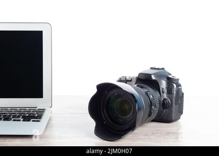 A closeup of a camera and a laptop on a wooden table Stock Photo