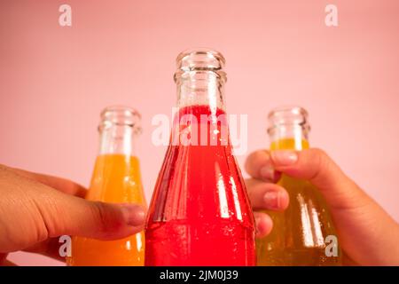 A closeup of hands holding bottles with colorful soda drinks Stock Photo