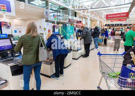 Supermarché Tesco, clients utilisant des terminaux de paiement libre-service pour payer leurs produits d'épicerie, Tesco fournit également le balayage comme service de magasin, Manchester, Royaume-Uni Banque D'Images