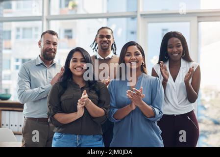 Nous avons atteint notre plus grand objectif. Portrait rogné d'un groupe diversifié d'hommes d'affaires debout ensemble et accroche dans le bureau. Banque D'Images