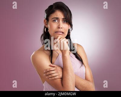 Oups ma mauvaise. Une belle jeune femme en incrédulité avec ses bras pliés et sa main reposant contre son menton sur un fond rose. Banque D'Images