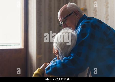 Un mari âgé affectueux et de soutien enferme et réconforte sa femme de derrière. Photo de haute qualité Banque D'Images